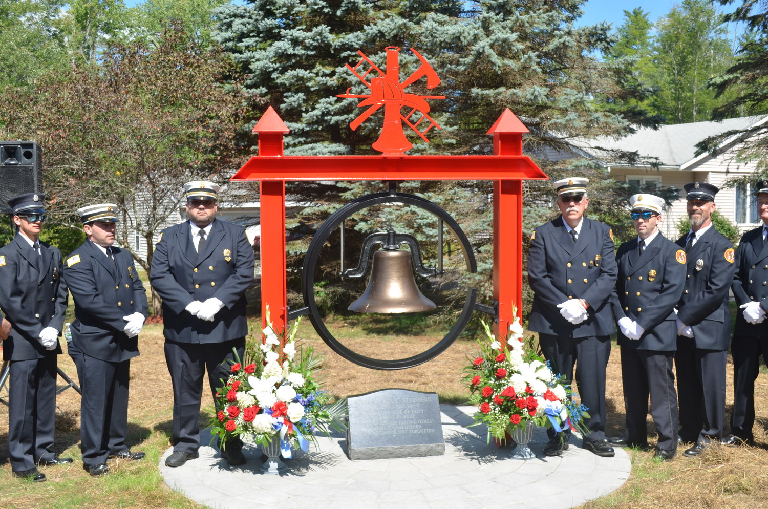The memorial in honor of William "Billy" Steinberg stands in place outside the Forestburgh Fire Company No. 1 building, flanked by firefighters.